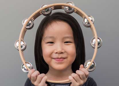 girl holding tambourine around face