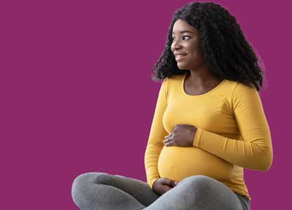 pregnant black woman sitting cross-legged with her hand on her belly