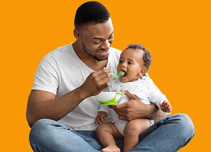 young black man spoon feeding a baby