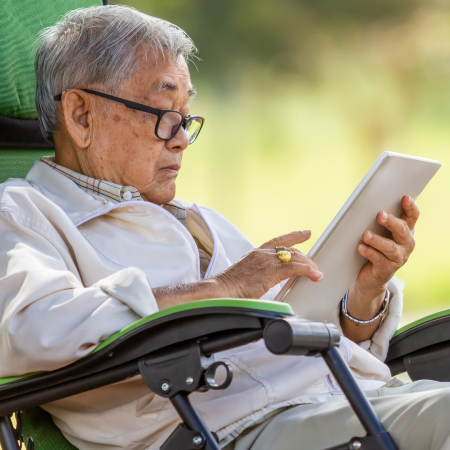man sitting down looking at an electronic tablet